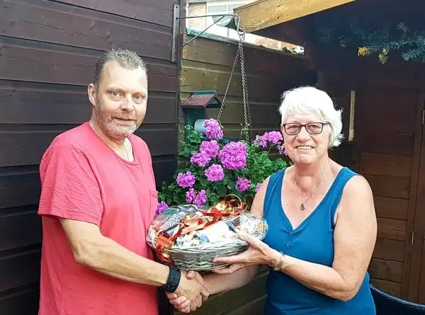 Klaas Veldhuis overhandigt het wijn en noten pakket aan Jennie Botter